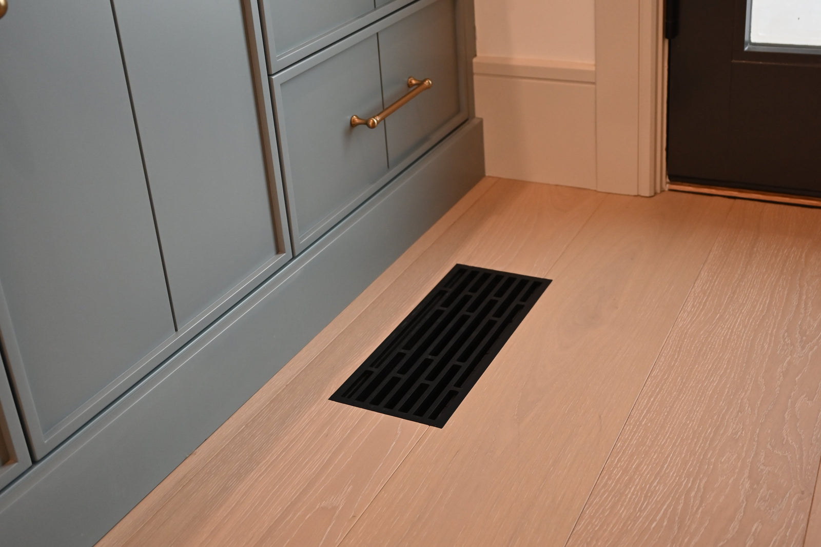 Straight · Matte Black flush floor vent in a wood floor