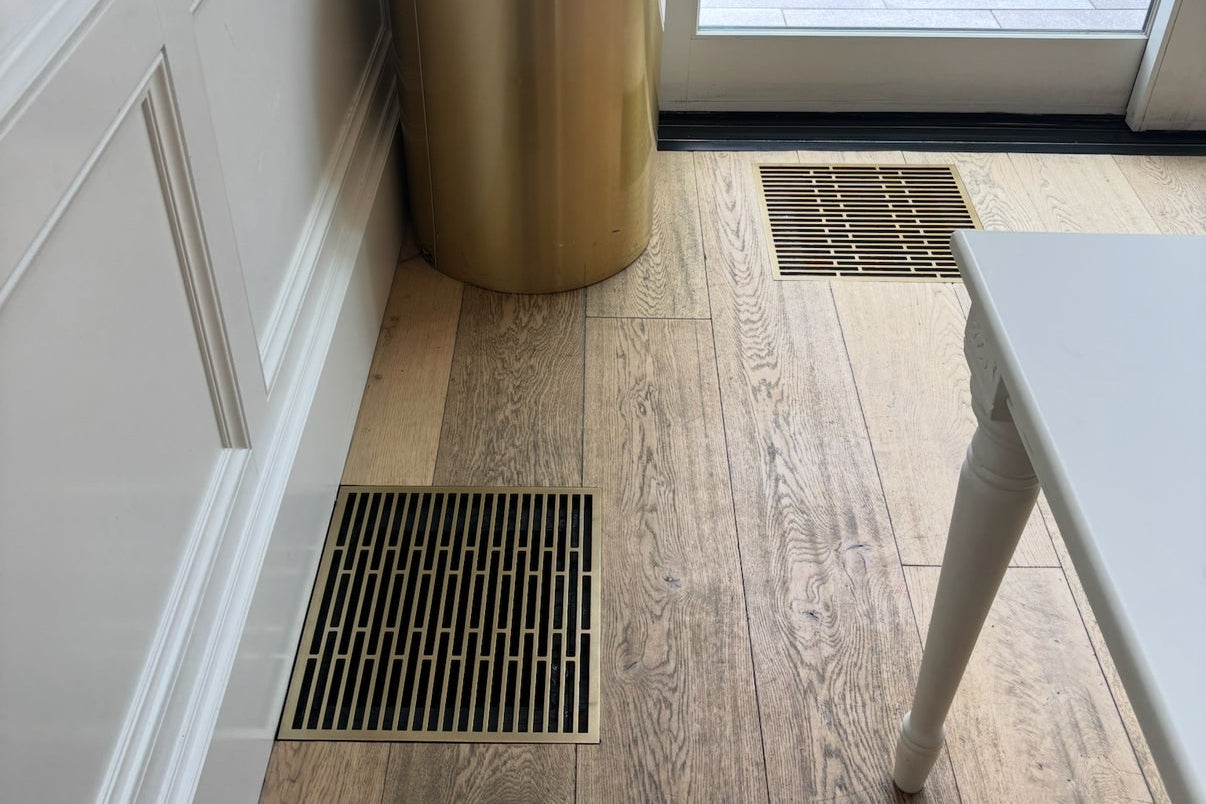 Straight · Vintage Gold flush floor vent in a wood floor